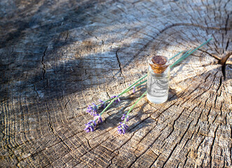 Bottle with healing anti-aging essential oil with lavender on a wooden background. Herbal medicine, skin care, copy space