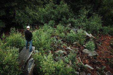 Aerial view to young man standing on stone in forest. Natural reserve javoricka vrchovina, dark mood green