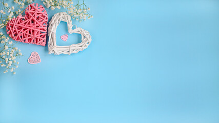 Composition for Valentine's Day, top view. Two hearts and white flowers on a light blue background with central space for design