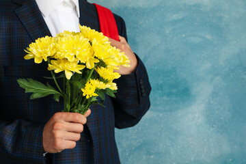 Schoolboy with backpack and chrysanthemums on blue background