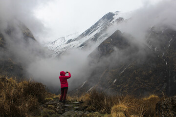 Trekker is taking a photo of clouded Machapuchare (Fishtail) in Himalayan mountains