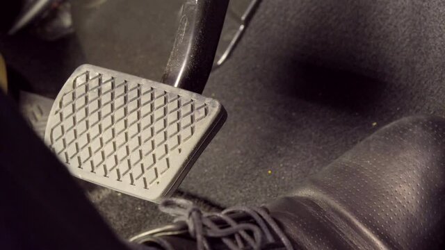 A man's foot pressing accelerator and brake wearing black leather shoes, HONDA car, Tokyo, Japan. March 2020. Camera fixed, extreme close-up, high angle view.