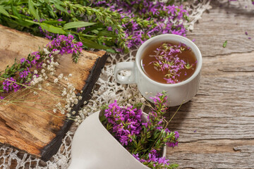 Fireweed is a healthy herbal tea. Mug of traditional russian drink ivan tea on a wooden background with fireweed flowers