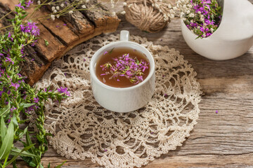 Fireweed is a healthy herbal tea. Mug of traditional russian drink ivan tea on a wooden background with fireweed flowers