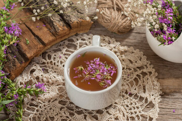 Fireweed is a healthy herbal tea. Mug of traditional russian drink ivan tea on a wooden background with fireweed flowers