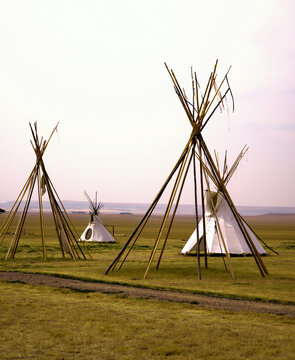 Teepee pole structure with covered teepees in background.