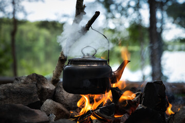Vintage camping kettle over open fire in summer forest, Close-up.