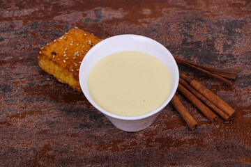 Condenced milk in the bowl with sinnamon and pastry
