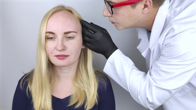 A doctor trichologist conducts a study of the hair of a blonde. Alopecia treatment. Hair loss, alopecia, itching, burning in the head, seborrhea or brittle ends