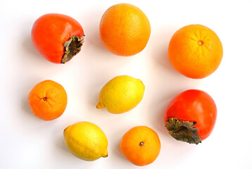 Juicy oranges, persimmons, tangerines and lemons on a white background.