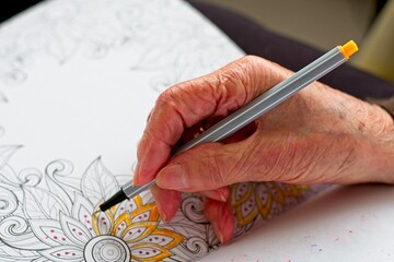 close-up old woman's hand coloring a drawing