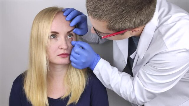 An ophthalmologist examines a woman who complains of a burning sensation and pain in her eyes. Eye fatigue from a computer screen or telephone (sand sensation on the cornea)