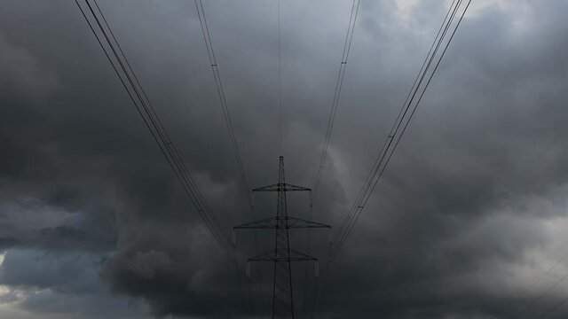 Time lapse summer dark storm clouds moving over forest and transmission electricity steel pylon tower