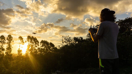 Boy flying a drone at sunset in brazil