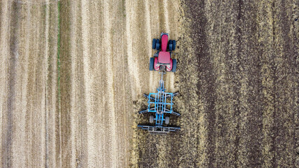 Aerial view of red tractor or combine harvester works in field. Industrial agriculture