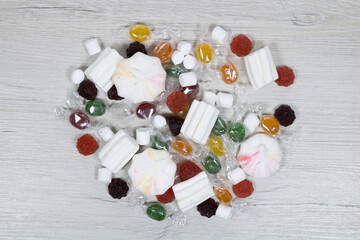 Multicolored candies in a transparent package on a background of bleached wood.