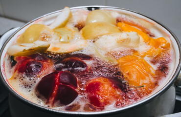 Fruit compote: apricots, plums, apples, cherries are cooked in a metal pan in boiled water with bubbles. Making juice.