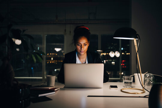 Dedicated young businesswoman working late while using laptop at creative office