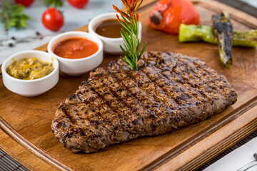 Fresh delicious juicy steak with vegetables on wooden background.