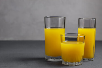 Orange juice in glasses on gray background