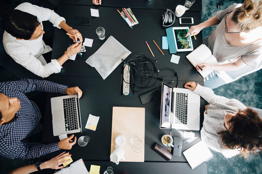 Businesswoman discussing with transgender colleague over laptop in board room during meeting
