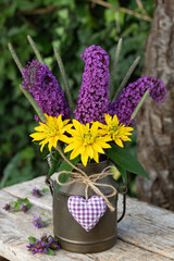 rustikaler Blumenstrauß mit Rudbeckia und Sommerflieder-Blüten in vintage Milchkanne