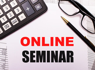 Fototapeta premium ONLINE SEMINAR written on a light sheet next to a calculator, black-framed glasses and a pen. Internet concept