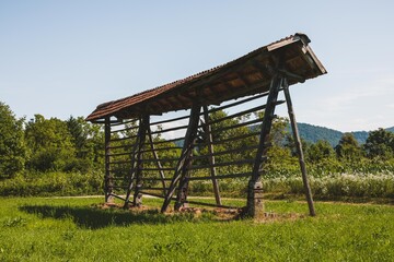Traditional, Slovenian building for drying hay in the middle of a beautiful, green meadow with blue sky