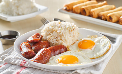 filipino silog breakfast with garlic fried rice, longsilog, and two sunny side up eggs