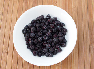 Ripe black raspberry berries on a white plate