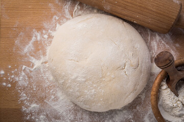 Homemade yeast dough freshly prepared for pizza or bread on wooden background.