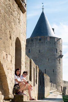 A mother and son on holiday and seated outside the main wall of the medieval castle, Carcassonne, Aude, Languedoc
