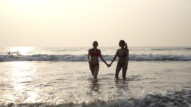 Young attractive girls girlfriend come out of the sea. Girls tourists on beach.