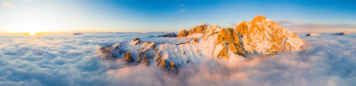 Panoramic aerial view of Grigne group mountain peaks emerging from mist at sunset, Lake Como, Lecco province, Lombardy