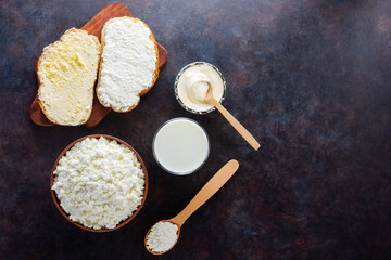 Various dairy products. Milk, cottage cheese and sour cream on a dark background. Bread with cream...