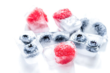 frozen blueberry and raspberry in ice cubes on white background