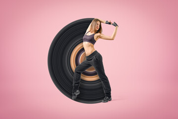 Young sporty woman dancer wearing black outfit on pink background