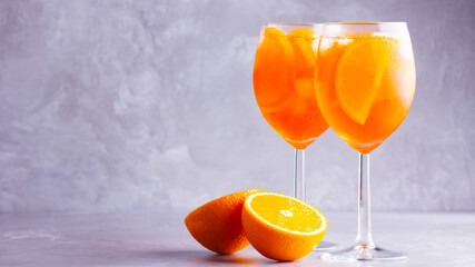 Aperol spritz cocktail on a gray background. Two glasses of aperol spritz with orange slised. Summer italian cocktail in glass. Copy space