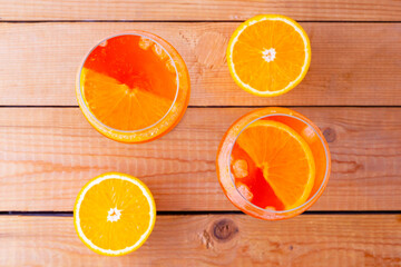 Aperol spritz cocktail on a wooden boards. Two glasses of aperol spritz with orange slised. Summer...