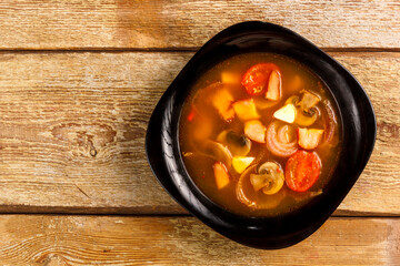 Traditional Thai Tom Yam soup in a black plate on a wooden table. Copy space