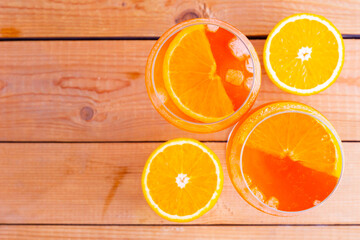 Aperol spritz cocktail on a wooden boards. Two glasses of aperol spritz with orange slised. Summer cocktail in glass. Top view. Copy space