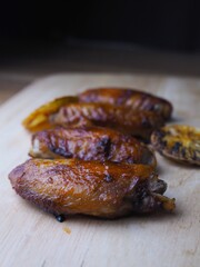Grilled chicken with thyme, garlic and lemon slices on a grill pan, shiitake mushroom on black background.