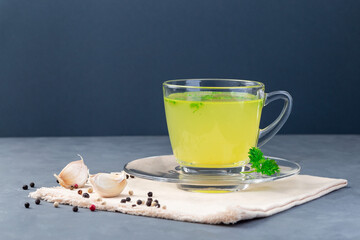 Chicken broth in glass cup with chopped parsley, horizontal