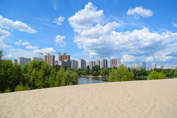 Fototapeta na wymiar View through the sand to green trees outside the city