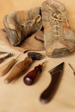 An old pair of  men's  brown shoes with shoemaker tool lying on leather material. Cobbler concept.