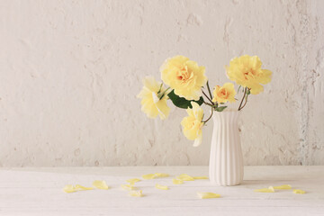 yellow roses in white vase on background white wall