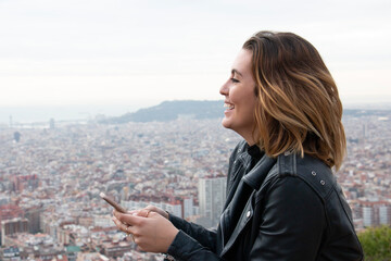 smiling young woman talks on her mobile phone with the city in the background