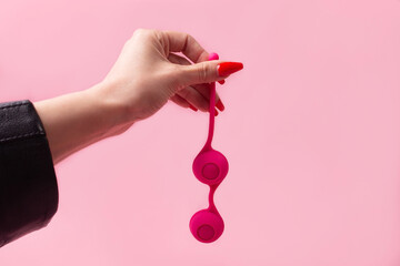 Dildo in hand on a pink background, sex toy