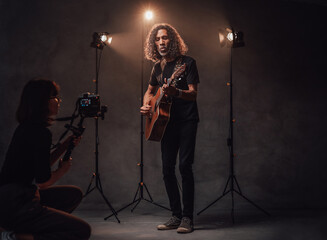 Videographer shoots how a talented Latin American musician playing guitar in the studio with stage lights
