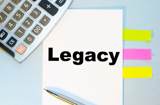 The text legacy is written on a notebook on a blue background with a calculator and pen.